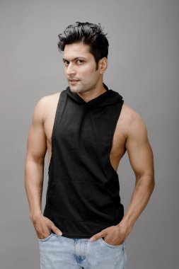 Sıradan giyinen Hintli genç erkek manken siyah tişört ve yırtık kot pantolon giyiyor. Erkek model. Moda Portresi.