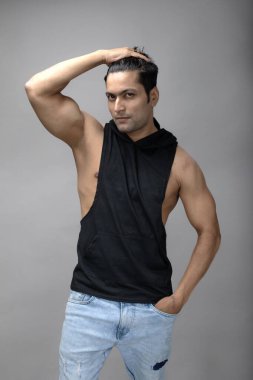 Sıradan giyinen Hintli genç erkek manken siyah tişört ve yırtık kot pantolon giyiyor. Erkek model. Moda Portresi.