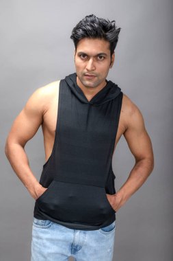 Sıradan giyinen Hintli genç erkek manken siyah tişört ve yırtık kot pantolon giyiyor. Erkek model. Moda Portresi.