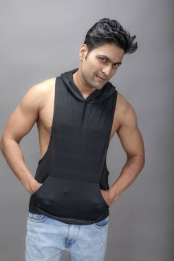 Sıradan giyinen Hintli genç erkek manken siyah tişört ve yırtık kot pantolon giyiyor. Erkek model. Moda Portresi.