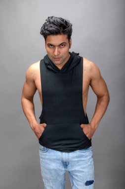 Sıradan giyinen Hintli genç erkek manken siyah tişört ve yırtık kot pantolon giyiyor. Erkek model. Moda Portresi.