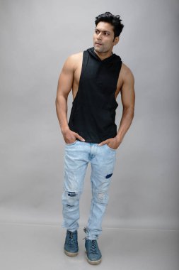 Sıradan giyinen Hintli genç erkek manken siyah tişört ve yırtık kot pantolon giyiyor. Erkek model. Moda Portresi.