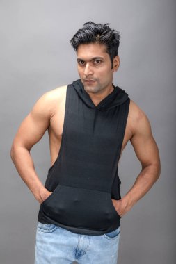 Sıradan giyinen Hintli genç erkek manken siyah tişört ve yırtık kot pantolon giyiyor. Erkek model. Moda Portresi.