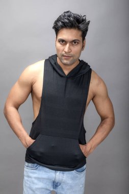 Sıradan giyinen Hintli genç erkek manken siyah tişört ve yırtık kot pantolon giyiyor. Erkek model. Moda Portresi.