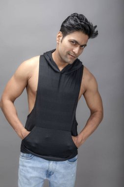 Sıradan giyinen Hintli genç erkek manken siyah tişört ve yırtık kot pantolon giyiyor. Erkek model. Moda Portresi.