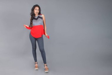 Genç, güzel bir Hintli kadın modelin gündelik kıyafetleriyle stüdyo fotoğrafı. Kırmızı ve gri tasarımcı bluzu ve beyaz arka planda siyah kot pantolon giyiyor. Kadın manken. Moda Portresi.
