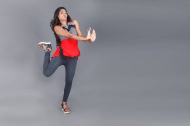 Genç, güzel bir Hintli kadın modelin gündelik kıyafetleriyle stüdyo fotoğrafı. Kırmızı ve gri tasarımcı bluzu ve beyaz arka planda siyah kot pantolon giyiyor. Kadın manken. Moda Portresi.