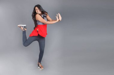 Genç, güzel bir Hintli kadın modelin gündelik kıyafetleriyle stüdyo fotoğrafı. Kırmızı ve gri tasarımcı bluzu ve beyaz arka planda siyah kot pantolon giyiyor. Kadın manken. Moda Portresi.