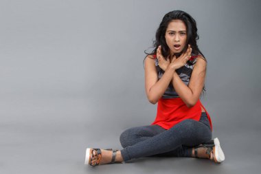 Gri arka planda kırmızı ve gri renkli ve mavi kot pantolon giyen, gündelik giyimli genç ve güzel bir Hintli kadın modelin stüdyo fotoğrafı. Kadın manken. Moda Portresi.