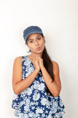 Genç ve güzel bir Hintli kadın modelin günlük spor kıyafetleri içinde beyaz arka planda mavi-beyaz bluz, mavi kot pantolon ve mavi başlık giyerken çekilmiş bir fotoğraf. Kadın manken. Moda Portresi.