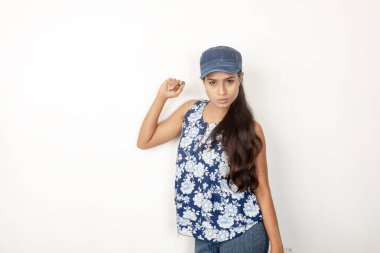 Genç ve güzel bir Hintli kadın modelin günlük spor kıyafetleri içinde beyaz arka planda mavi-beyaz bluz, mavi kot pantolon ve mavi başlık giyerken çekilmiş bir fotoğraf. Kadın manken. Moda Portresi.