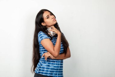 Mavi bluz giyen, su bardağı tutan ve camdan su içen genç, siyah saçlı bir manken. Sağlıklı yaşam tarzı ve cilt bakımı, doğal güzellik. Reklam için ateş et .