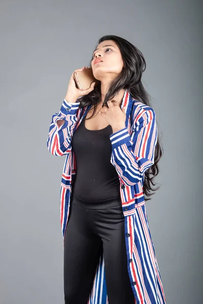 Beautiful woman wearing black leggings, black top and red, blue, white striped tunic. Female model in casual wear, advertisement shot.