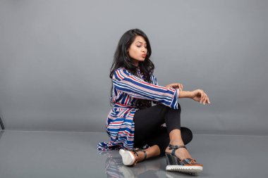 Topuklu sandalet, siyah tayt ve kırmızı, mavi, beyaz çizgili tunik giyen güzel bir kadın. Ayakkabı ürünü gösteren kadın modeli, reklam çekimi.