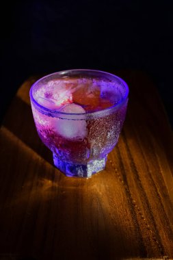 Masanın arkasındaki neon lambalarda şeffaf bir cam. Kokteyl, parti ve gece hayatı konsepti.