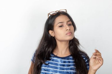 Genç ve güzel bir Hintli kadın modelin günlük kıyafetleri içinde, mavi ve beyaz baskılı bluzu ve beyaz arka planda temiz bir gözlüğü var. Reklam çekimi. Göz ürünü çekimi.