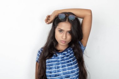 Genç ve güzel bir Hintli kadın modelin günlük kıyafetleri içinde, mavi ve beyaz baskılı bluzu ve beyaz arka planda temiz bir gözlüğü var. Reklam çekimi. Göz ürünü çekimi.