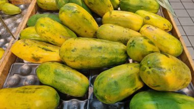 Tahta bir sandıkta sıralanmış olgun papayalar koleksiyonu..