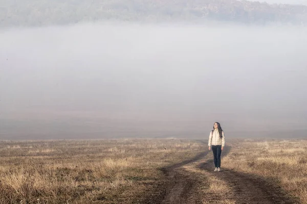 Misty  ground road filled with fog rural road countryside people girl  women walking Early morning landscape.  mist Autumn. minimalist Lonely sunrise Foggy Weather beautiful