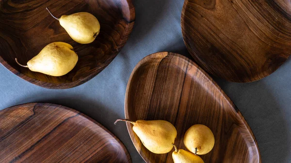 El yapımı ceviz yuvarlak ahşap palet, ahşap doğrama tahtası boş armut gri arka plan kasesi ahşap halkalar el yapımı ahşap sehpa sehpası koyu kahverengi tepsi servis ediliyor.