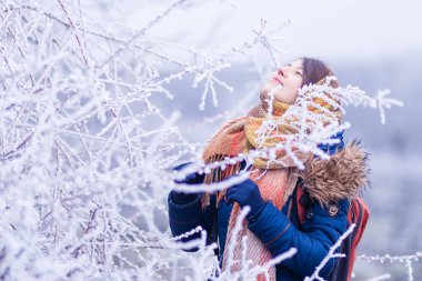 girl portrait Conception of winter holidays. park Cheerful girl in warm orange  clothes playing with snow outdoors near the beautiful forest blue  snowy branch hoar Attractive young woman.