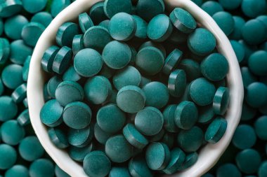 Green Organic Spirulina in algae pills tablets  bamboo wood  spoon rich in iron Close-up Super food concept healthy.
