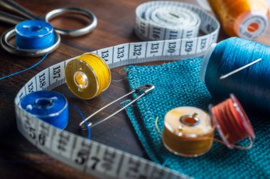 Dikiş malzemeleri - yüksük, iğne, mezura, mavi iplik makaraları, iğneler dahil. Arkaplana dikmek için mavi kumaş.