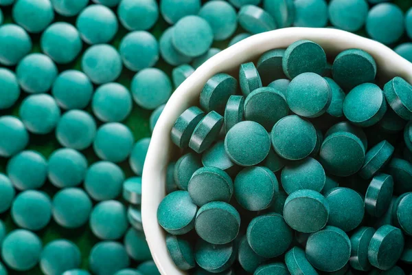 Green Organic Spirulina in algae pills tablets  bamboo wood  spoon rich in iron Close-up Super food concept healthy.