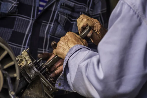 Two old men Auto mechanic working on car rusty engine in mechanics garage. Repair service close-up wrinkled dirty hands blue clothes Gear truck  Disassemble wrench home