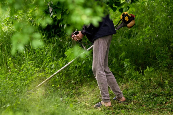 Caucasian Gardener working man Manual hand grass cutter  Weed Cutter or Power Weeder or Brush Cutter Lawn Mowe  Gasoline close up