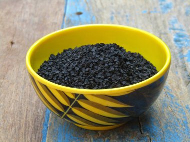 Eski ahşap arka planda bir kasede soğan tohumları 