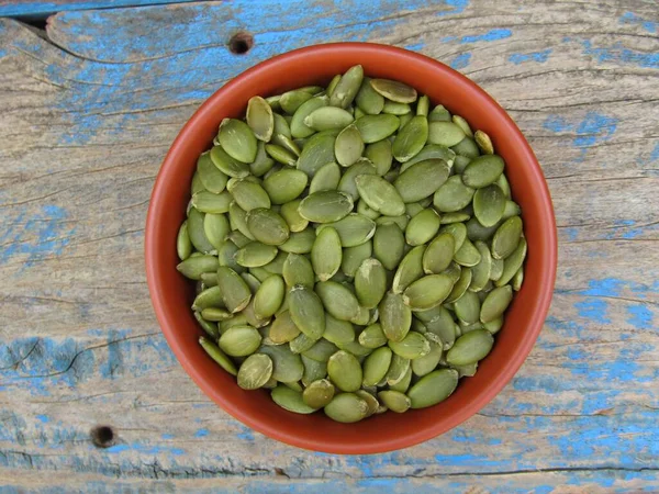 Eski ahşap arka planda bir kasede kabak tohumları 