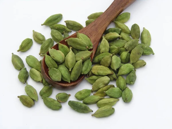 Elettaria kakule ya da beyaz arka planda tahta kaşıkta yeşil kakule. 