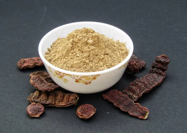 Acacia concinna or Shikakai powder in a bowl on black background 