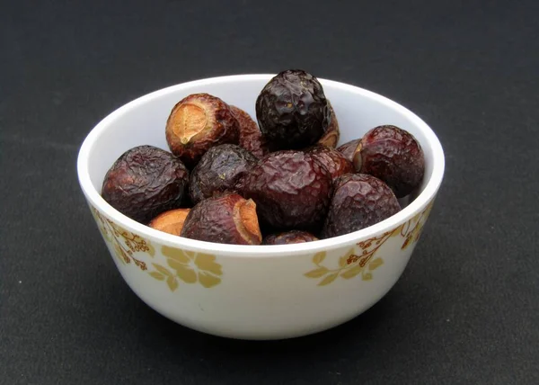 Sapindus mukorossi or Indian soapberry in a bowl on black background 
