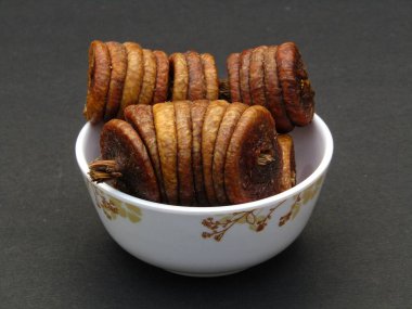 Siyah arka planda bir kasede kurutulmuş incir meyvesi. 