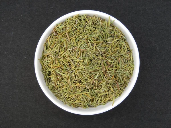 Kurumuş biberiye yaprakları siyah arka planda bir kâse üst görüşünde 