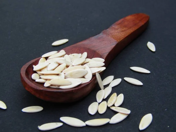 Siyah arka planda tahta kaşıkta salatalık tohumları 