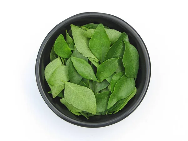 Curry leaves in a bowl on white background top view 