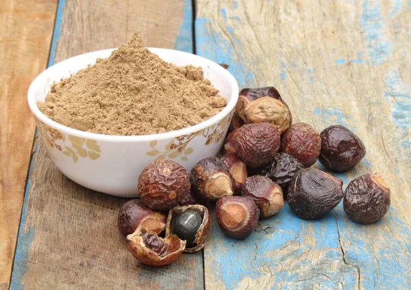 Sapindus mukorossi or Indian soapberry powder in a bowl on wooden background 
