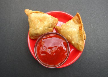 Hint atıştırmalıkları Samosa domates ketçaplı siyah arka plan 