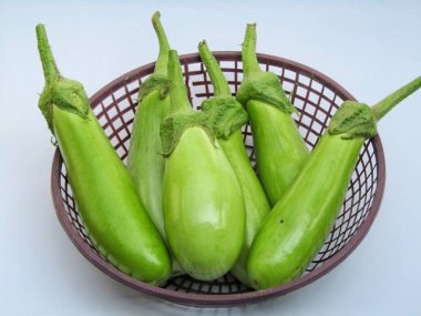 Beyaz arka planda bir sepette taze yeşil brinjal 