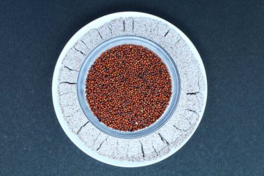 Eleusine coracana ya da parmak darı tohumu ve toz bir tabağın üst görünümünde