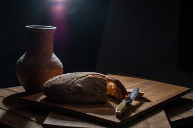 Tahta bir masada ekmek ve kil vazo..