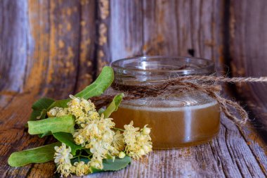 Ahşap zemin üzerinde ıhlamur balı ve ıhlamur çiçeği kavanozu