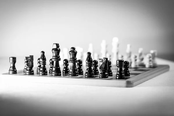 棋盘上两个国际象棋队一个排在另一个前面 被白色的背景隔离了高质量的照片 — 图库照片