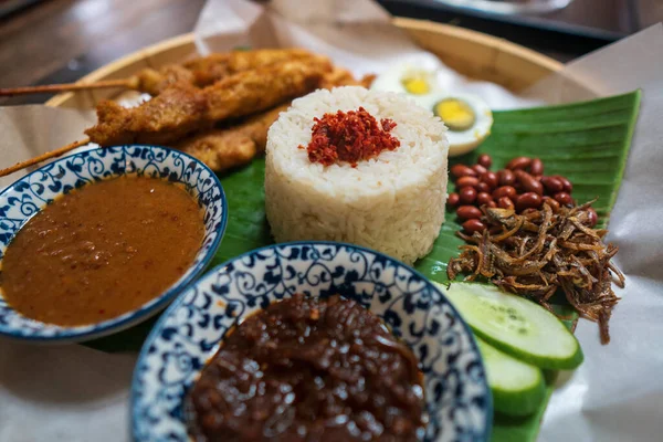 stock image Asian food Nasi Lemak is a rice dish infused with coconut milk. Served with sambal, fried anchovies, fried peanut, boiled eggs, and fresh cucumber. High quality photo