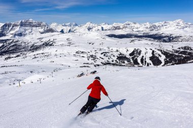 Kayakçı, Banff Ulusal Parkı 'ndaki Sunshine Village Kayak Merkezi' nde güneşli bir günün tadını çıkarıyor..