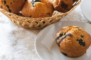 Freshly baked blueberry muffins in basket and in plate in front with space for text