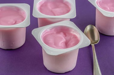 Mor arka planda çözünmüş fincanları olan pembe yoğurt fincanı - çocuk yoğurdu - soğuk bardaklarda yoğunlaşma